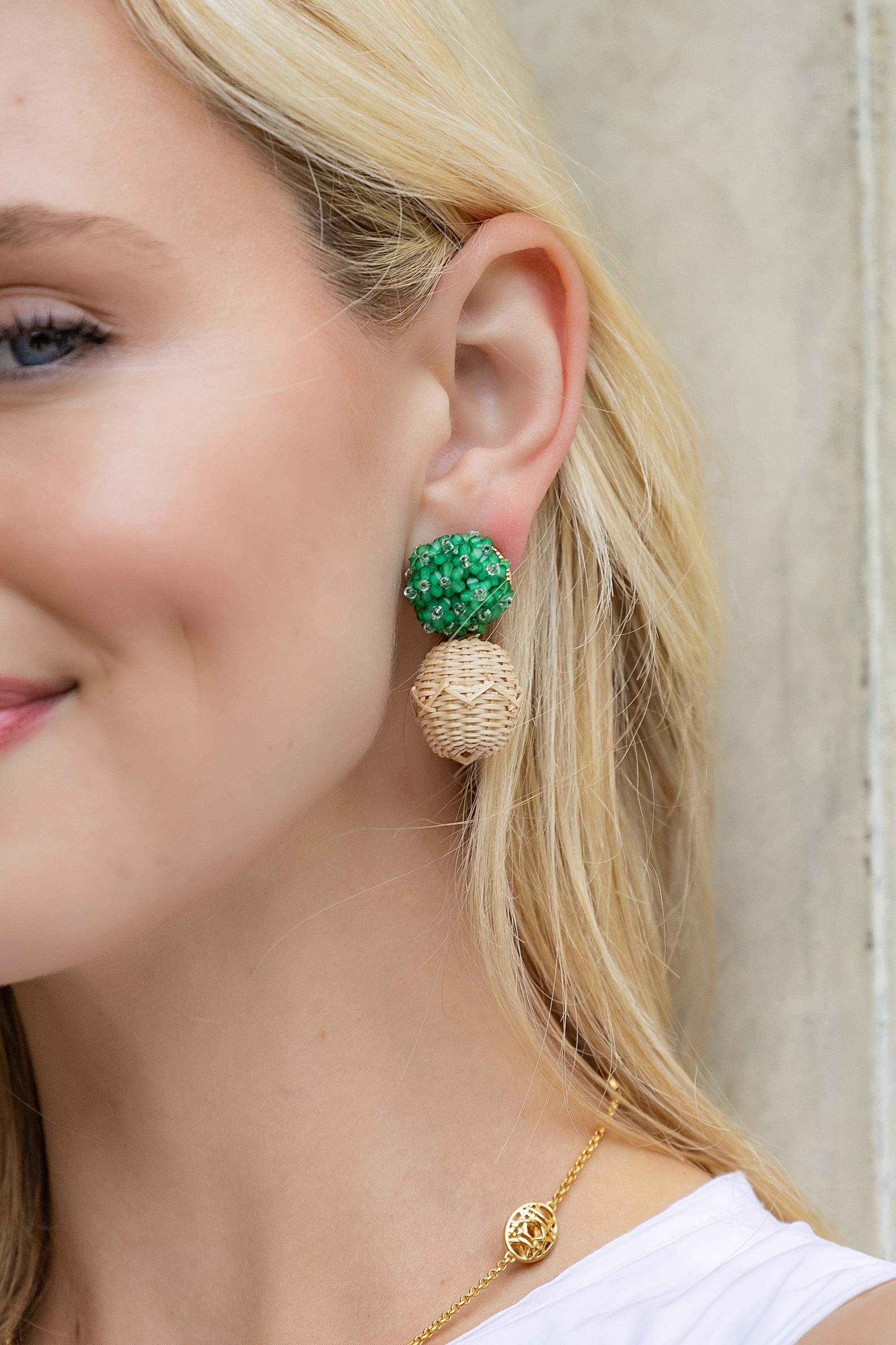 Close-up of a woman wearing green and beige earrings with a neutral background_m donohue collection