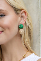 Close-up of a woman wearing green and beige earrings with a neutral background_m donohue collection