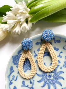 Ava Blue Rattan Teardrop earring displayed with white florals and blue ceramic dish_m donohue collection